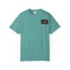 A teal t-shirt with a small black and red graphic on the left chest.