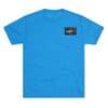 Bright blue T-shirt with a small black and yellow logo patch on the chest.