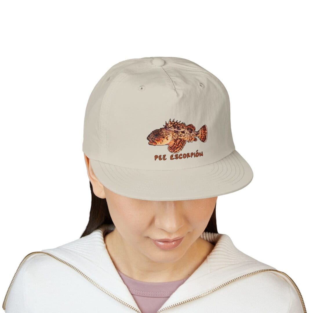 A person wearing a beige cap with a brown graphic on the front.