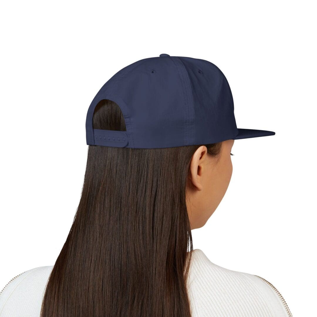 Rear view of a person with long hair wearing a navy blue cap.