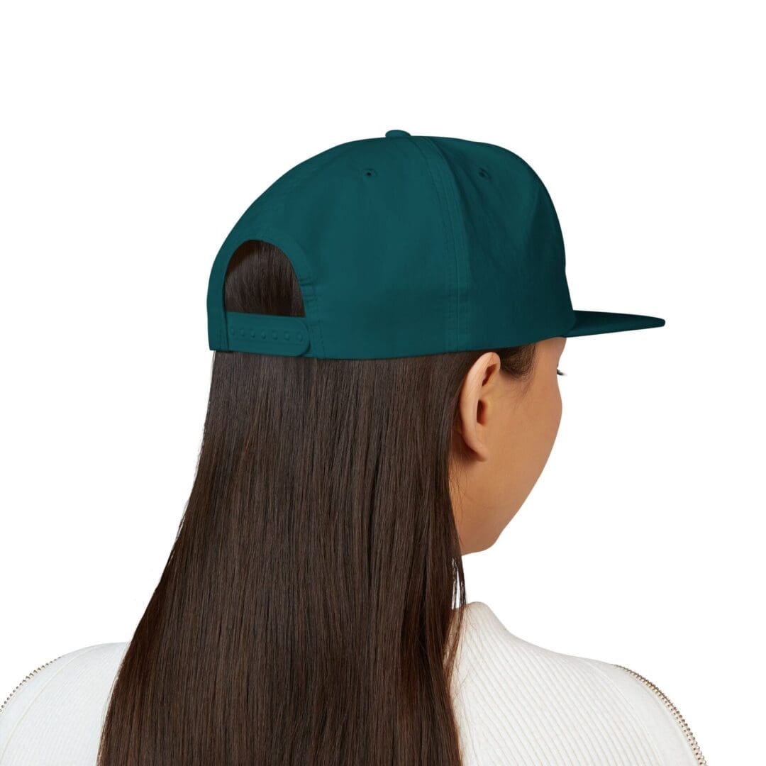 Person with long hair wearing a dark green baseball cap backward.