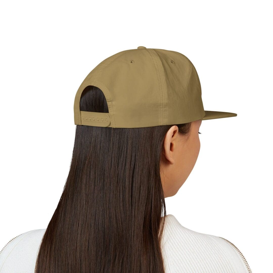 Person wearing a beige baseball cap backwards with long hair.