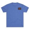 Blue T-shirt with a small black and red patch on the chest.