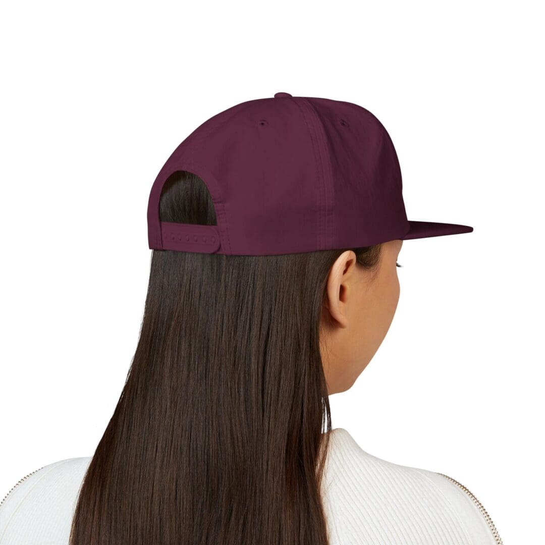 Back view of a person wearing a maroon cap and white shirt.