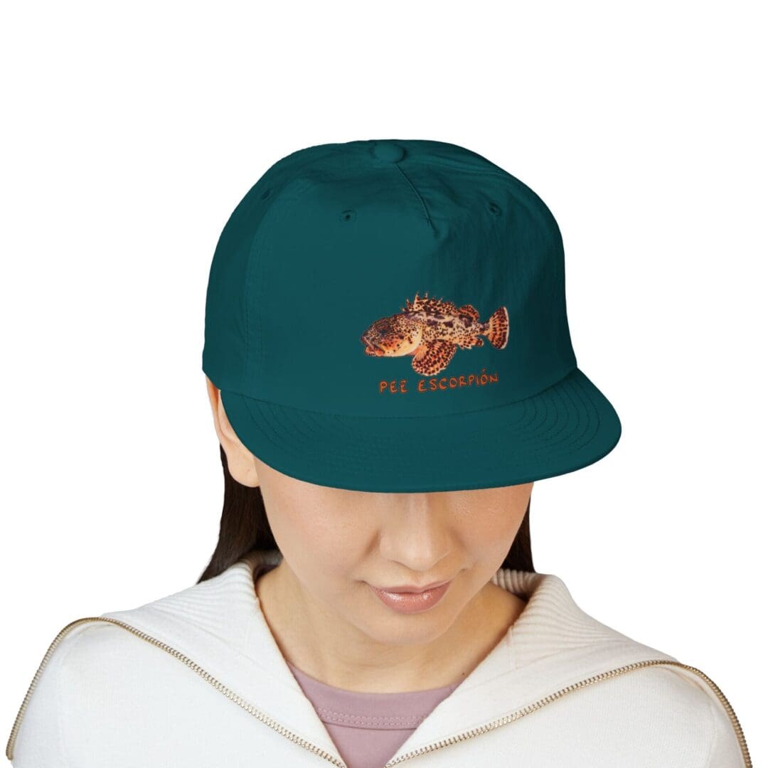 A person wearing a teal baseball cap with an embroidered design.