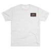 White T-shirt with a small rectangular black and brown patch on the chest.