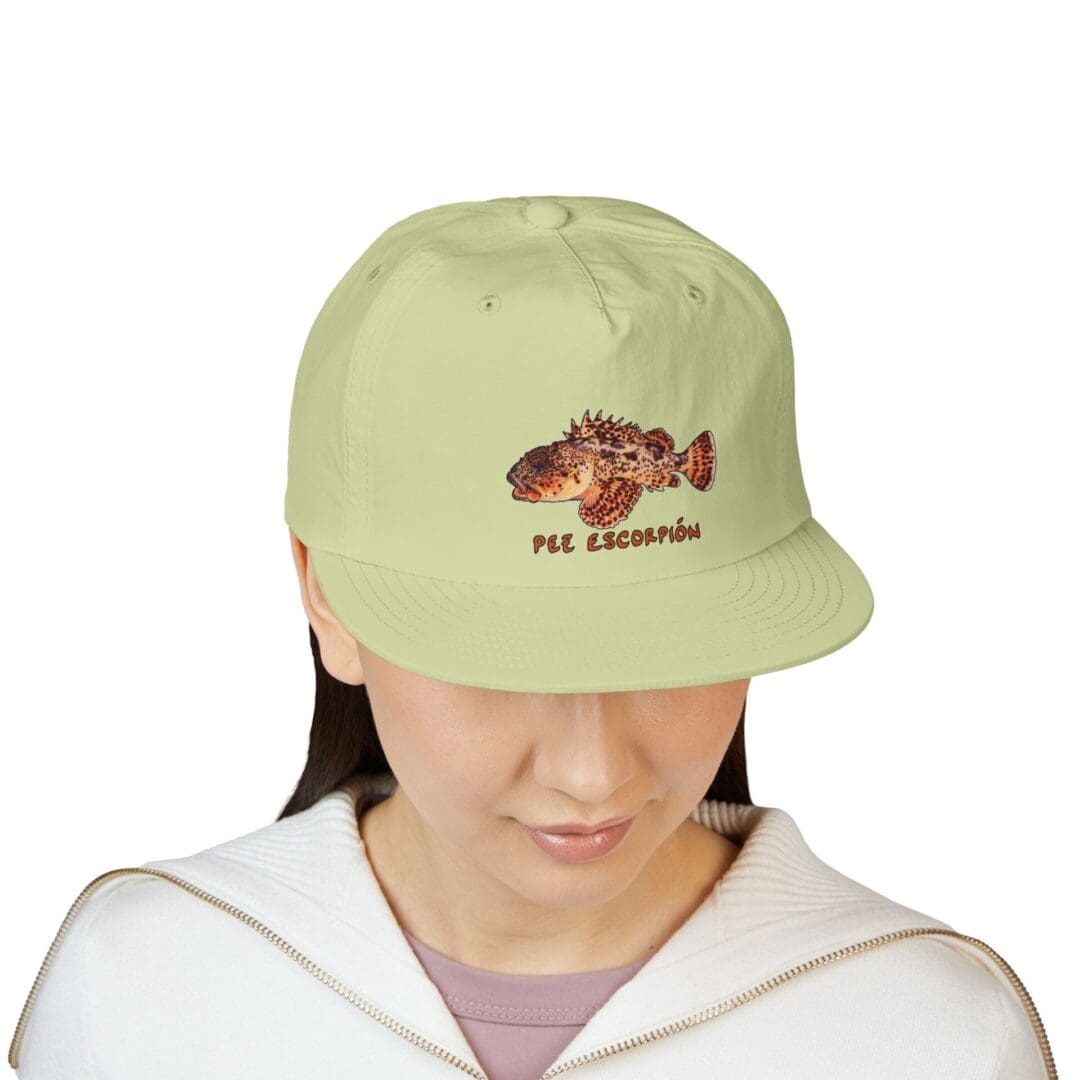 Person wearing a light green cap with a dinosaur design.