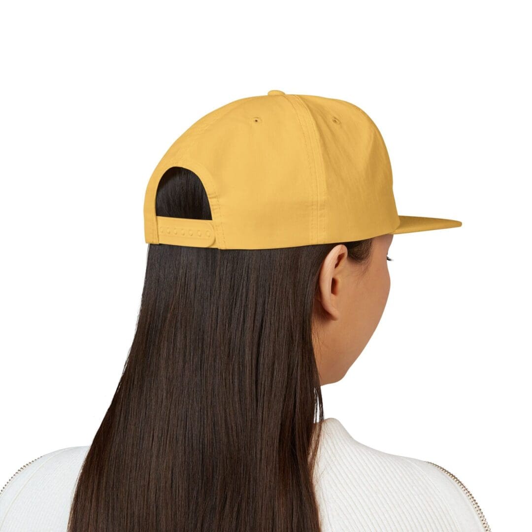 Person with long hair wearing a yellow cap facing away.