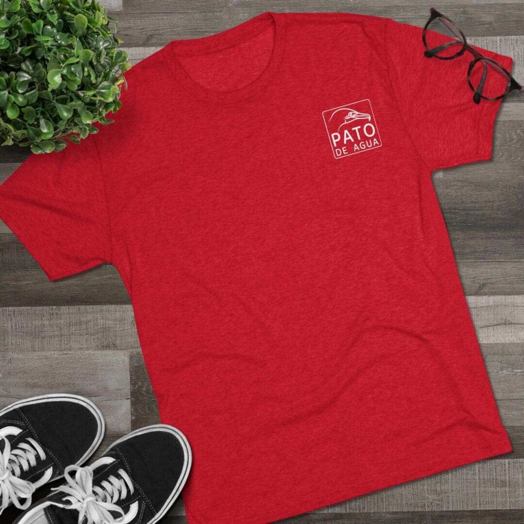 Red Polo Ralph Lauren t-shirt on a wooden floor with sneakers nearby.