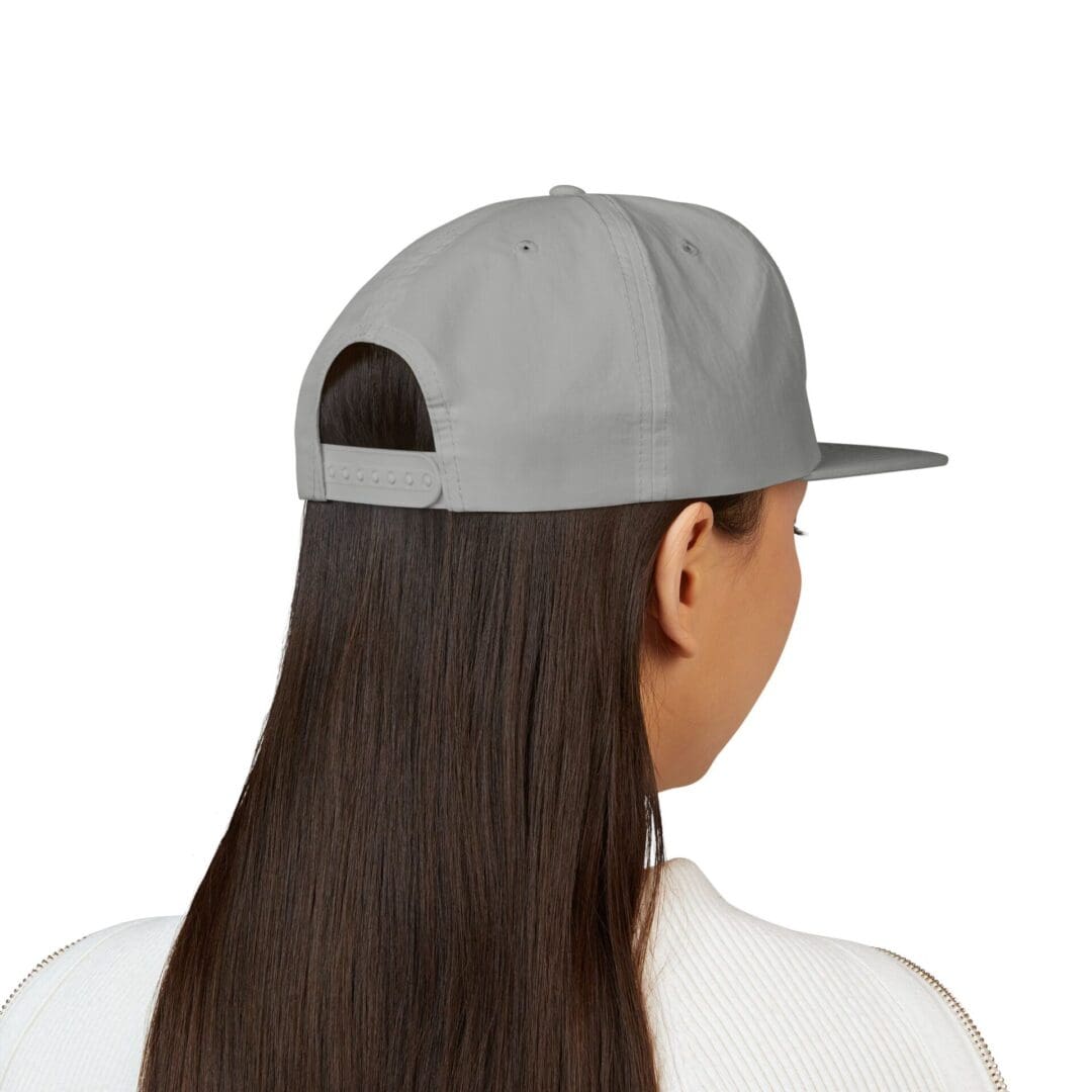 Woman with long hair wearing a grey baseball cap backward.
