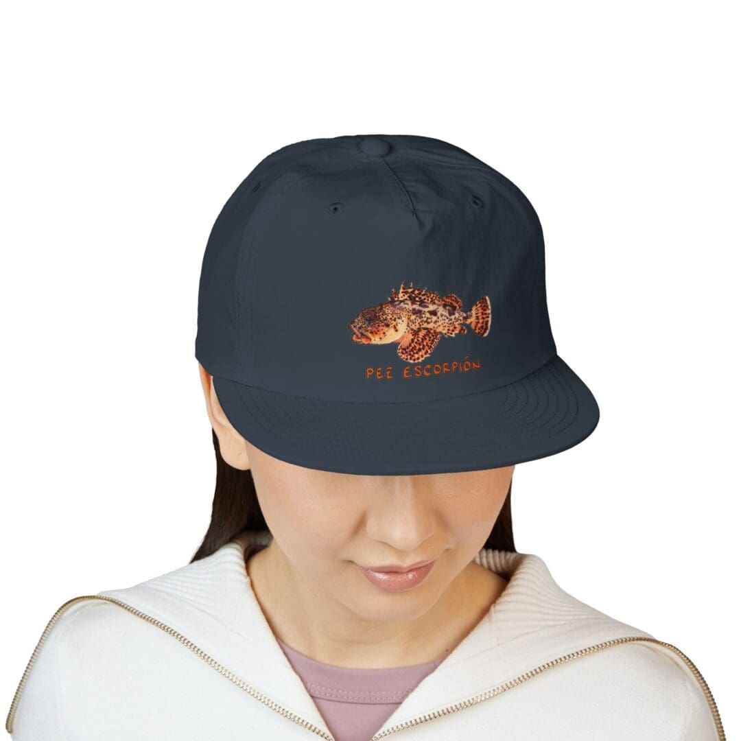 Person wearing a dark cap with a fish design.