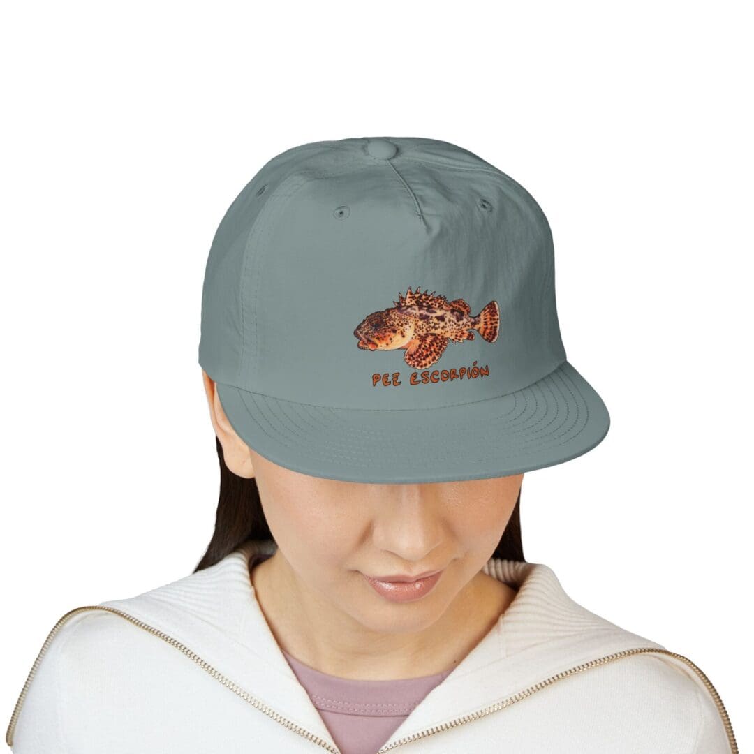A person wearing a grey cap with a fish design.