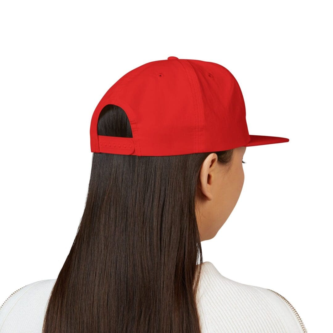 Back view of a person with long dark hair wearing a red cap and white shirt.